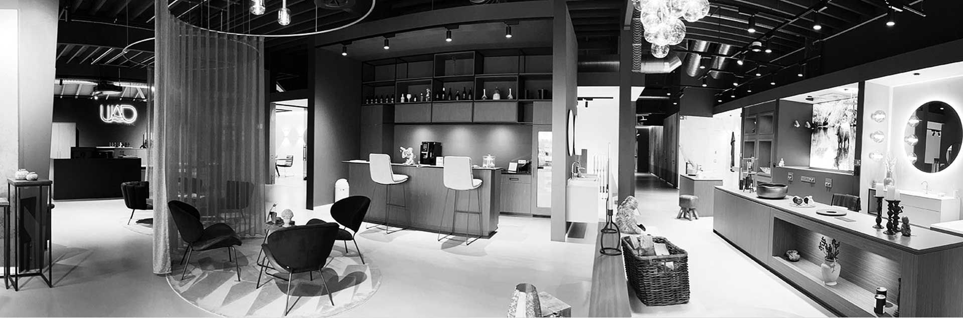 Ein Panorama der Gesamten Ausstellung in Schwarz Weiß. Es ist eine Sehr moderne eingerichtete Badausstelung im dunklen und peppigen Stil