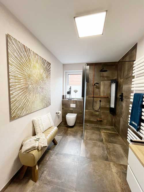 Hochwertiges Badezimmer mit dunklen Fliesen, Kupfer-Akzenten und großzügiger Glasdusche