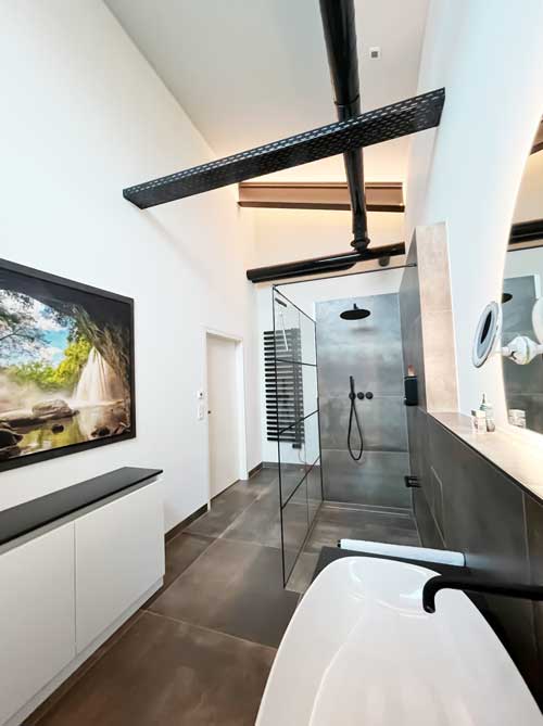 Modernes Bad mit begehbarer Dusche, großformatigen Fliesen und schwarzer Armatur im Industrial-Stil
