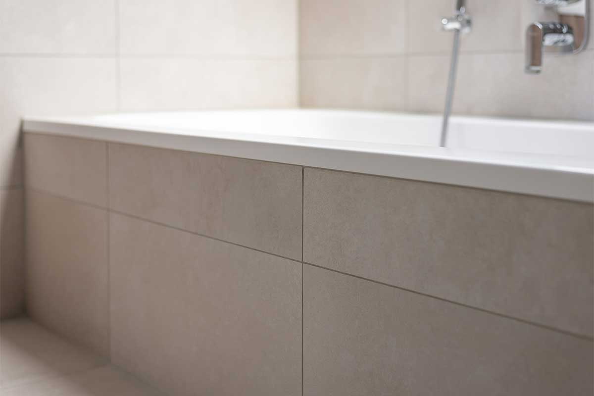 Große Badewanne mit klaren Linien und beiger Fliesenverkleidung.