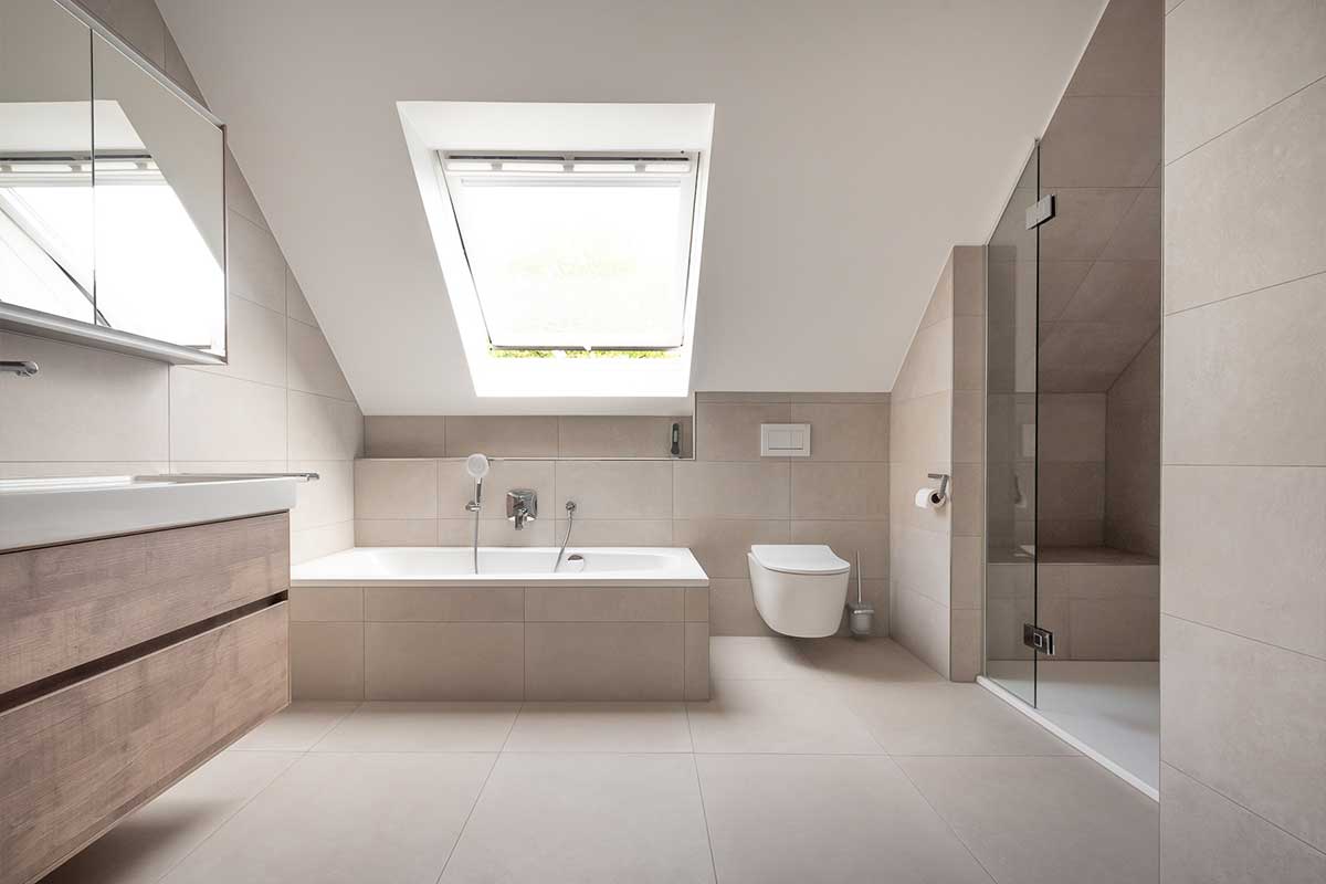 Helles Badezimmer mit Badewanne, WC und Dusche unter der Dachschräge.