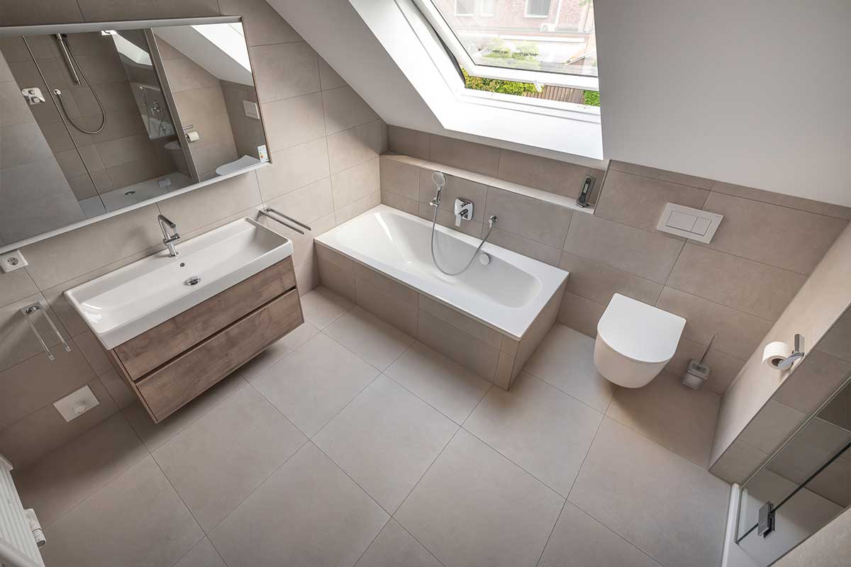 Modernes Bad mit Wanne, Waschtisch und WC, Tageslicht durch Dachfenster.