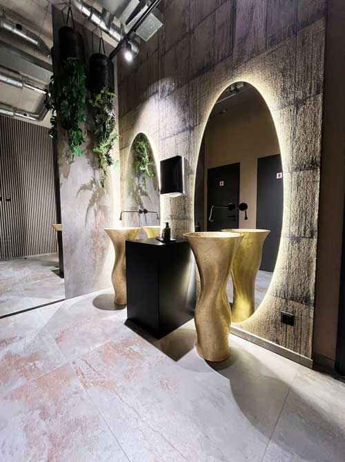 Extravagantes Waschplatz-Design mit goldenen Waschsäulen, beleuchteten Spiegeln und urbanem Loft-Charakter