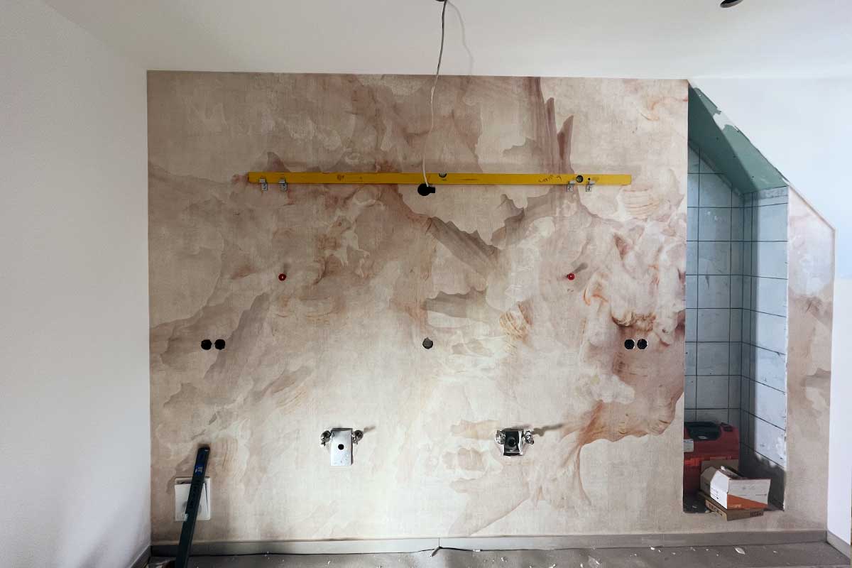 Rohbauzustand des Badezimmers mit vorbereiteter Wandgestaltung in Marmoroptik und Aussparungen für Waschplatzinstallationen.