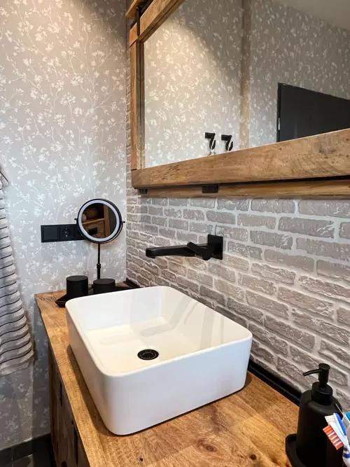 Rustikaler Holzwaschtisch mit Aufsatzwaschbecken, Spiegel und heller Ziegelwand im nordischen Badezimmer