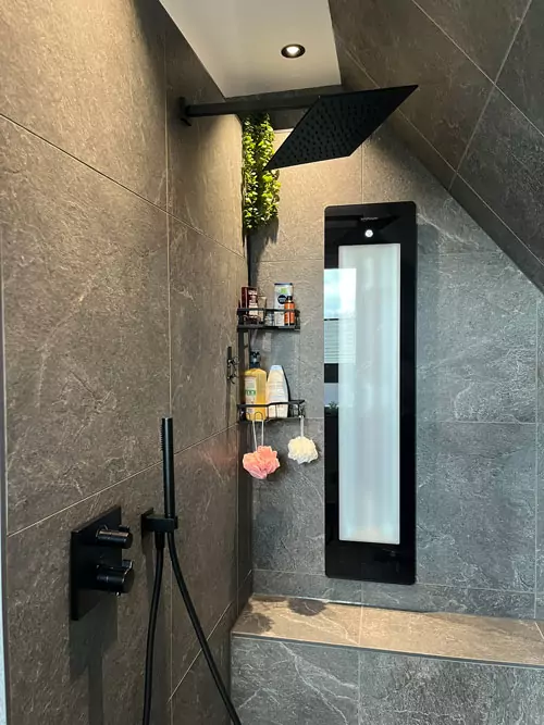 Moderne Dusche mit schwarzer Regendusche, Natursteinfliesen und integrierter Sitzbank